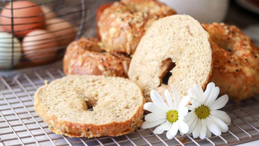 closeup of a stack of homemade freshly milled sourdough bagels cut in half with everything bagel seasoning sprinkled on top.