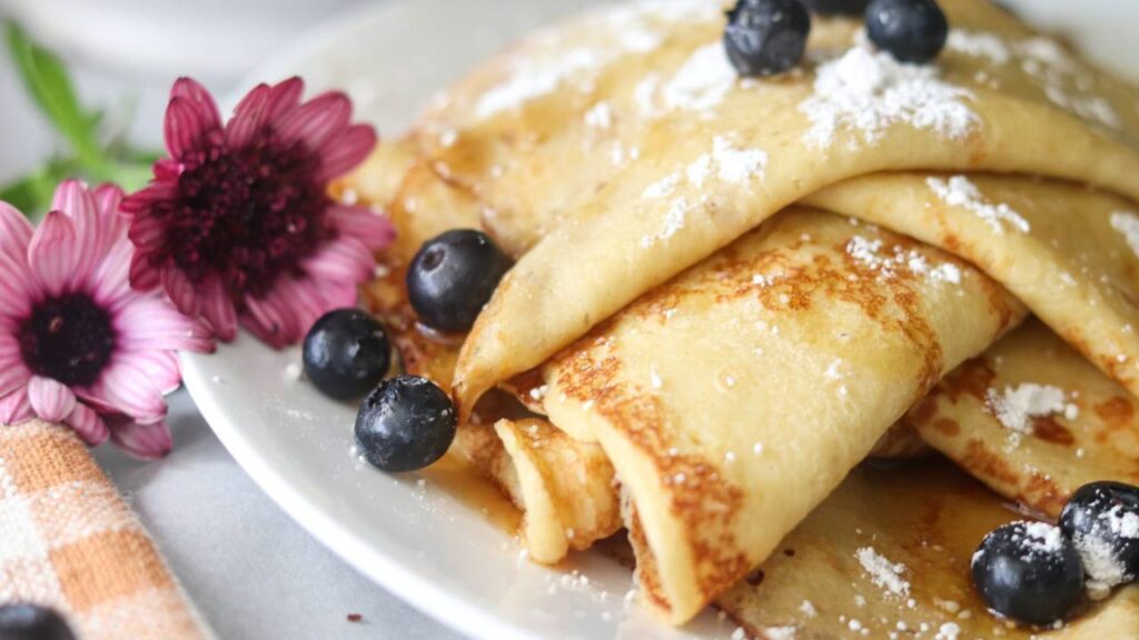 Folded sourdough discard crepes topped with powdered sugar and blueberries.
