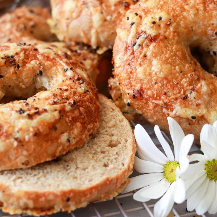 closeup of homemade freshly milled sourdough bagels cut in half with everything bagel seasoning sprinkled on top.