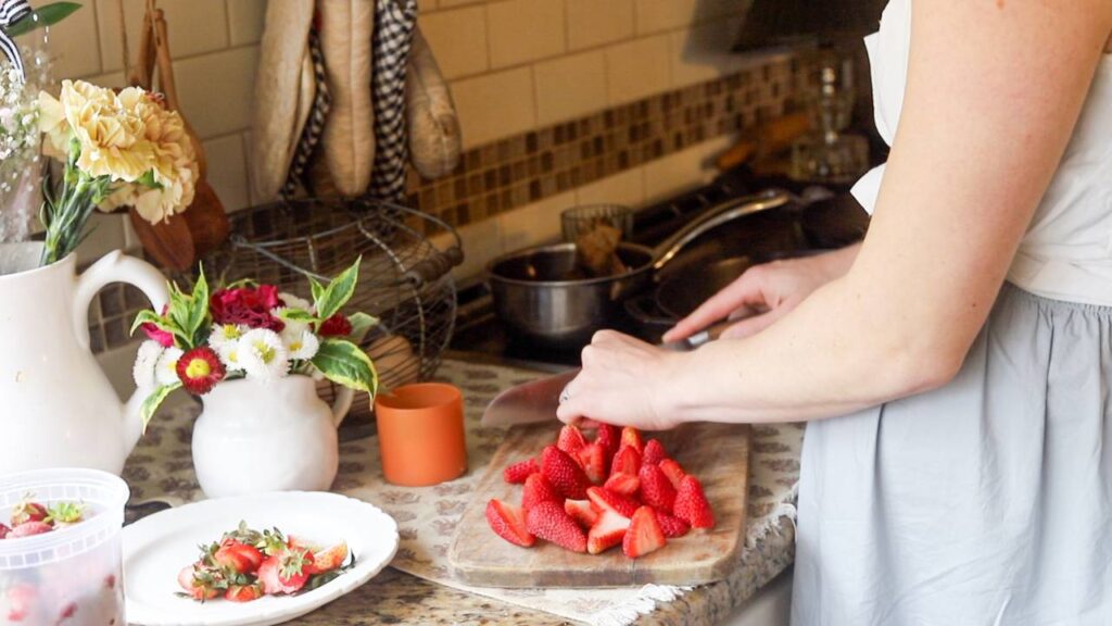 Slicing fresh strawberries on a cutting board in a cozy kitchen.