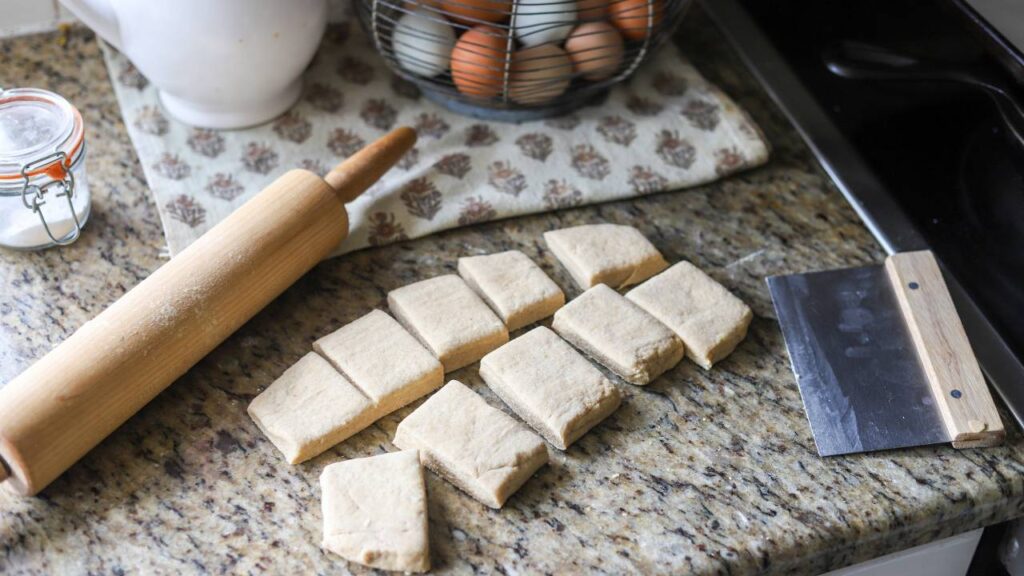 Rectangular biscuit dough pieces cut and ready to bake on a kitchen counter.
