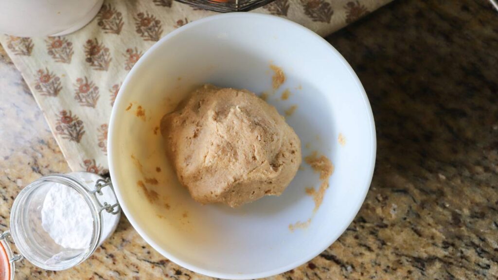 Ball of biscuit dough resting in a white mixing bowl on the counter.