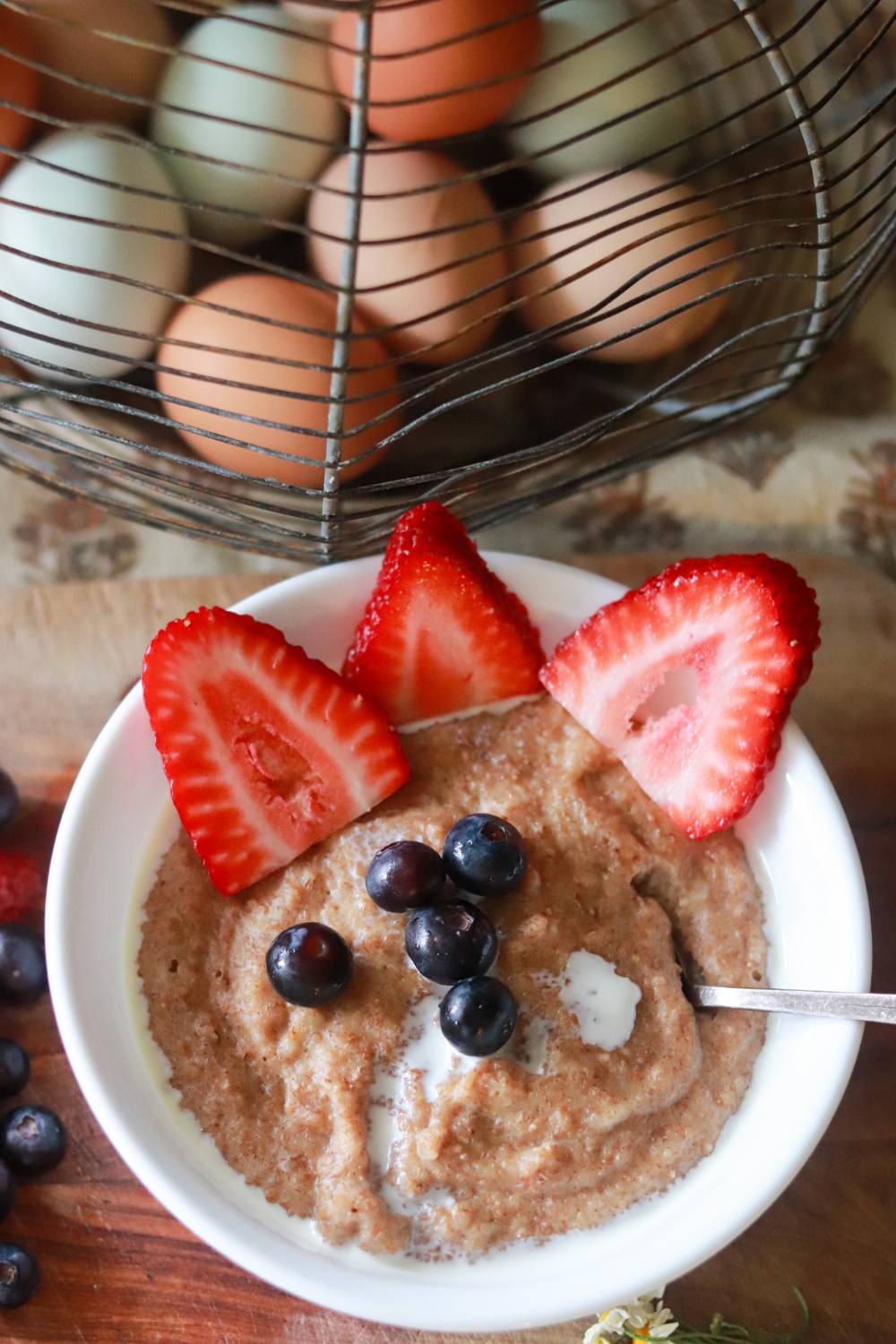 Bowl of cream of wheat topped with strawberries and blueberries.