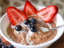 Bowl of cream of wheat topped with strawberries and blueberries.