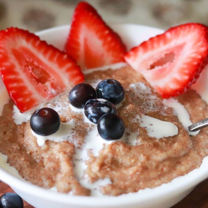 Bowl of cream of wheat topped with strawberries and blueberries.