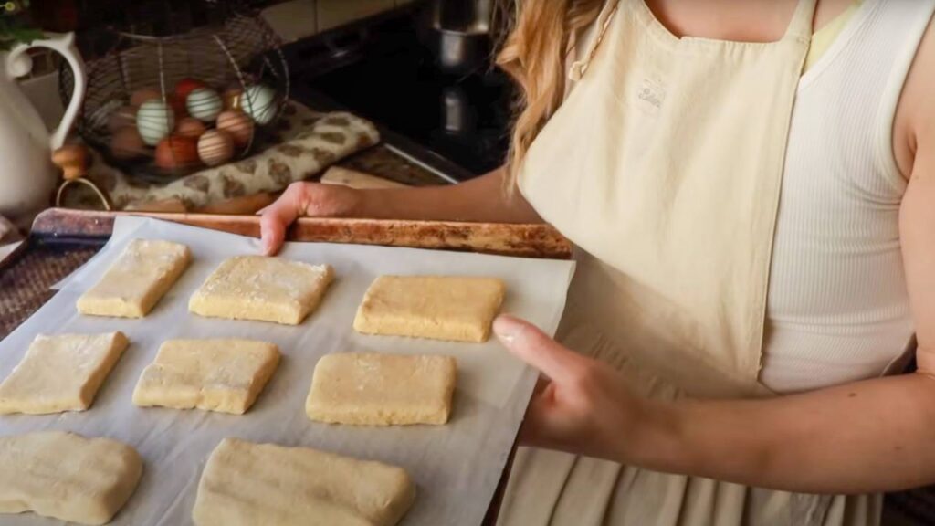 Woman holding a tray of unbaked biscuit dough.