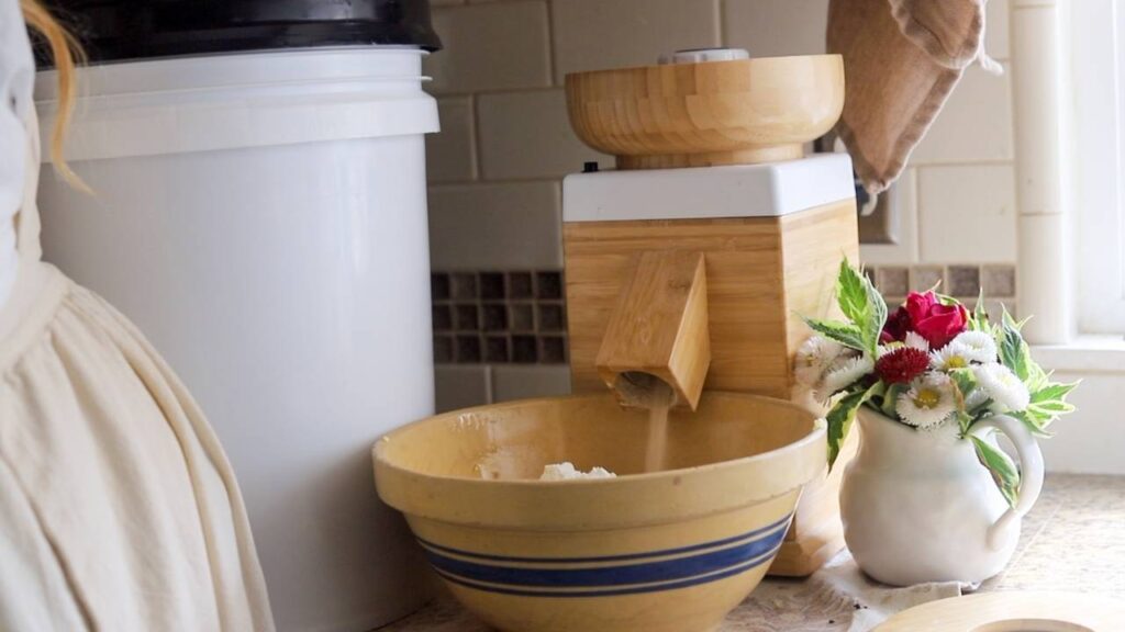 Fresh flour being milled into a bowl on a kitchen counter.