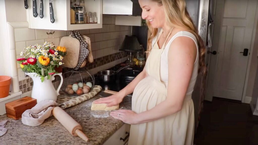 Woman shaping biscuit dough on a kitchen counter.