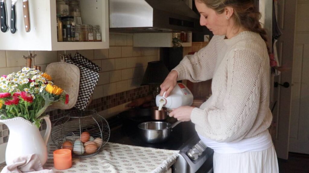 Woman pouring milk into a saucepan on the stove.
