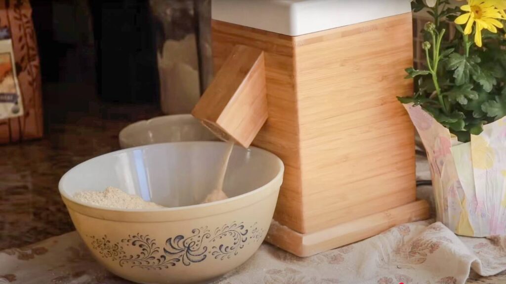 Flour being poured into a bowl from a grain mill.