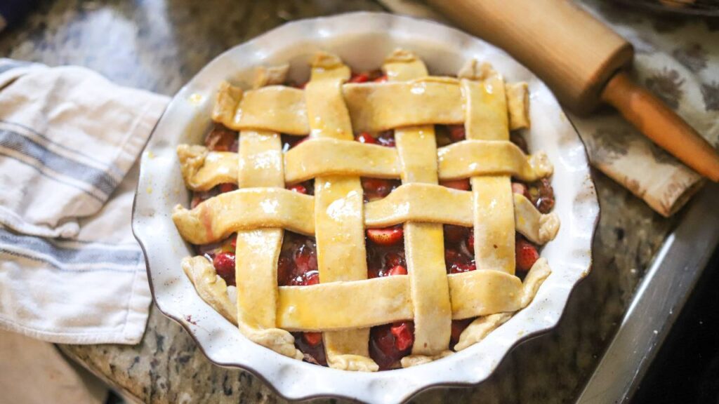 Unbaked strawberry pie with a lattice crust brushed with egg wash, ready to bake.