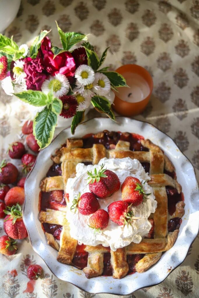 Finished strawberry pie topped with whipped cream and fresh strawberries.