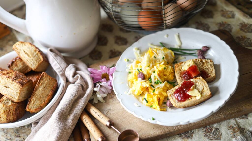 Breakfast plate with scrambled eggs and toast topped with butter and jam.