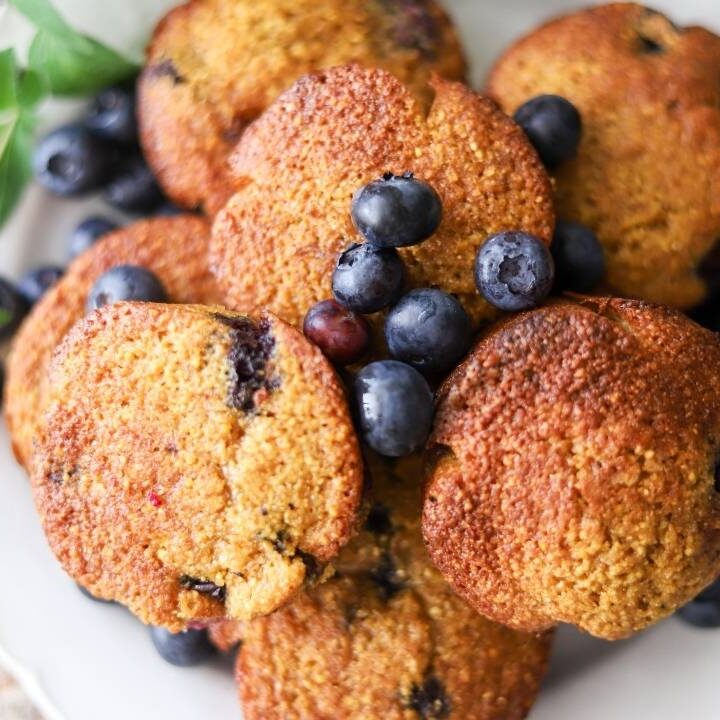 plate of blueberry muffins stacked on top of each other garnished with fresh blueberries