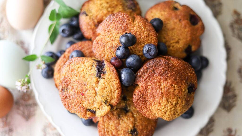 Plate of blueberry muffins topped with fresh berries.