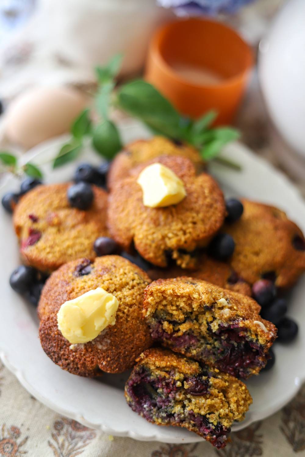 Plate of blueberry muffins, one cut open with melted butter on top.