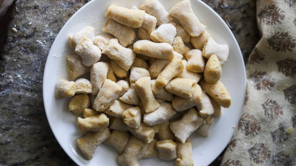 Plate of uncooked, floured gnocchi pieces ready to cook.