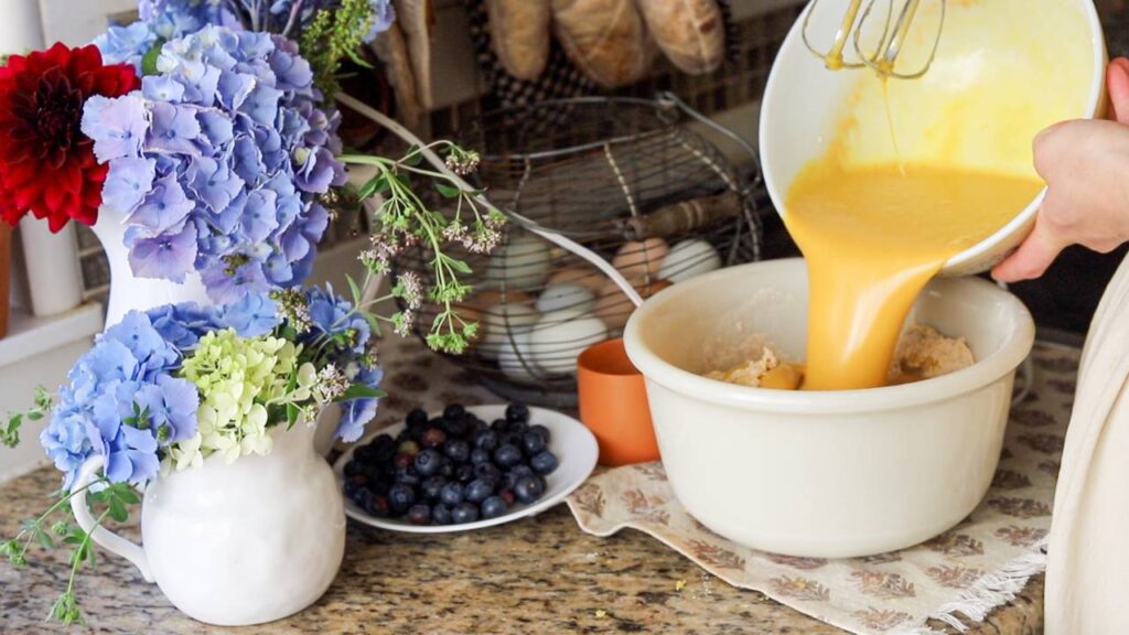 Pouring wet ingredients into a mixing bowl.