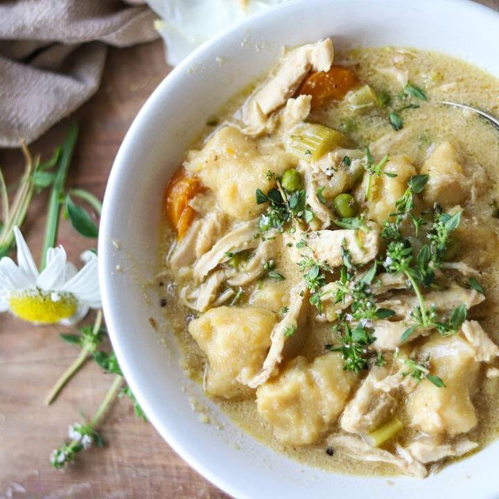 Bowl of chicken gnocchi soup with vegetables and herbs.