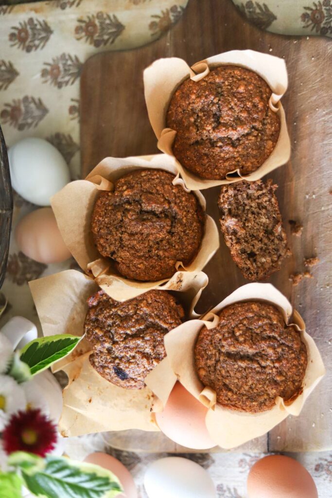 Overhead view of muffins in parchment paper with eggs around