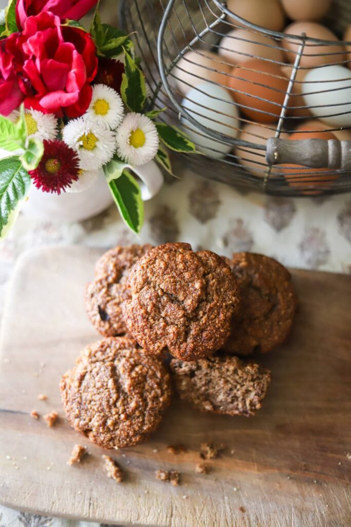 Muffins and flowers next to a basket of eggs.