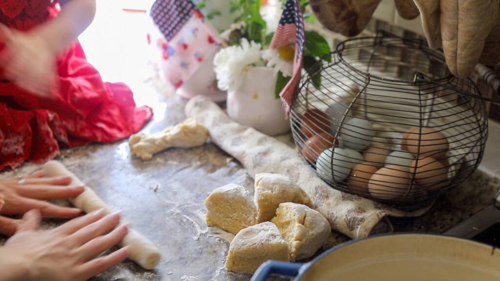 Hands rolling out gnocchi dough beside cut portions.