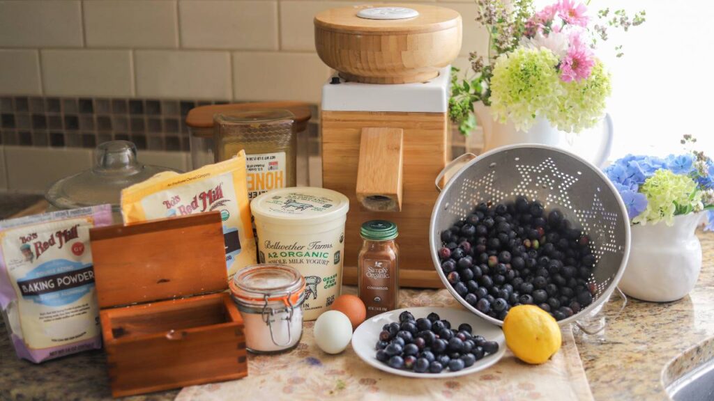 Baking ingredients and fresh blueberries on a counter.