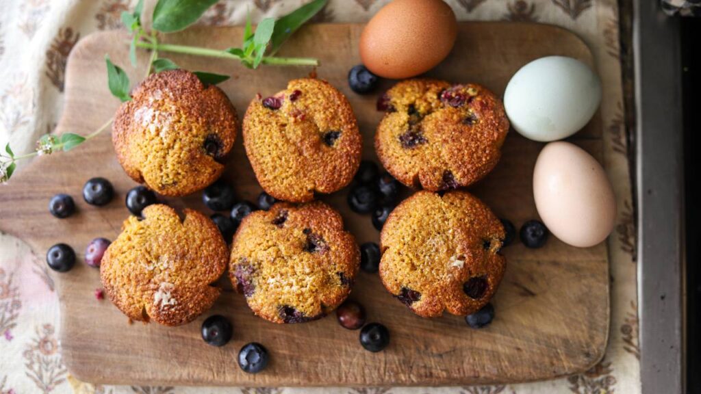Freshly baked blueberry muffins on a cutting board.
