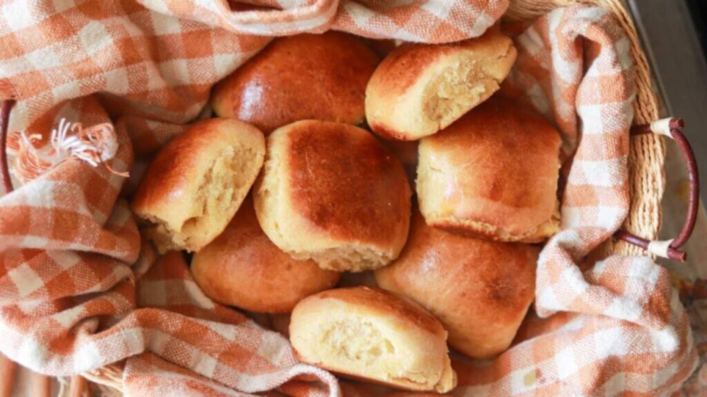 Basket of golden brown dinner rolls with checkered cloth