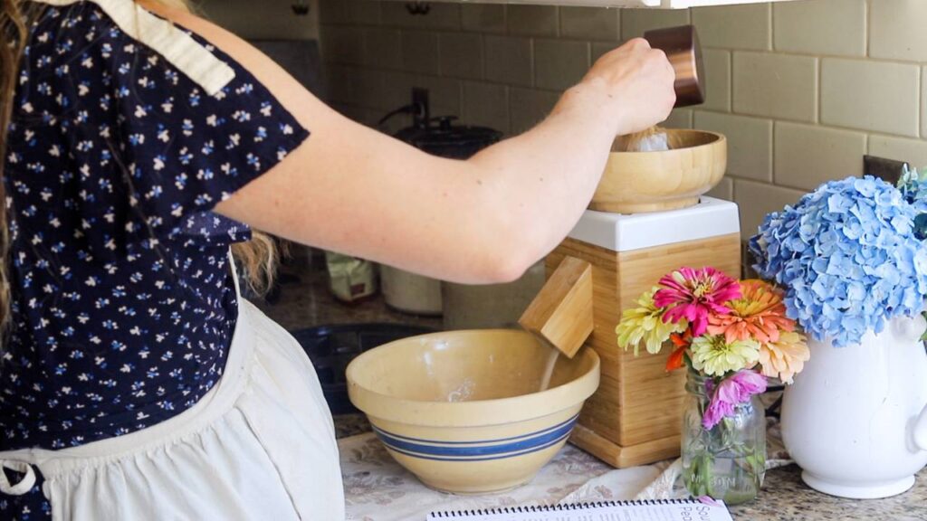 Pouring grain into a grain mill on a kitchen counter