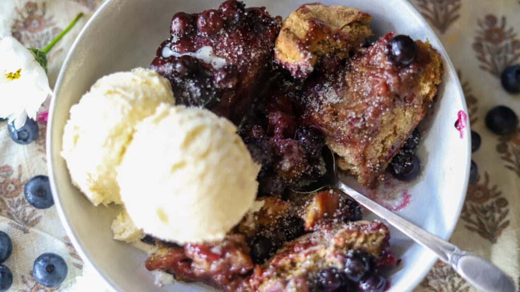 Blueberry cobbler served in a bowl with vanilla ice cream