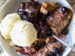 Blueberry cobbler served in a bowl with vanilla ice cream