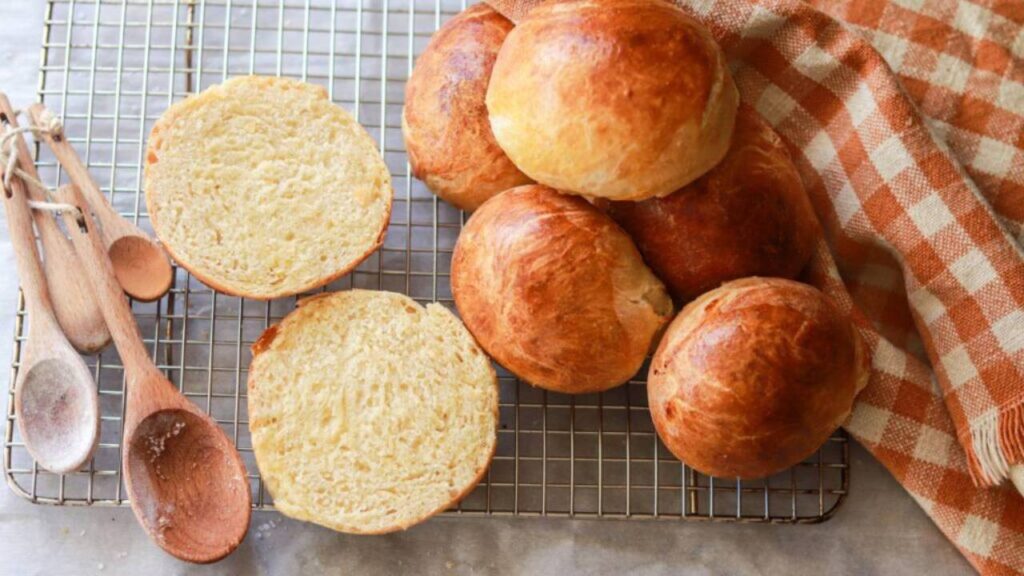 Sourdough hamburger buns on a cooling rack with wooden spoons