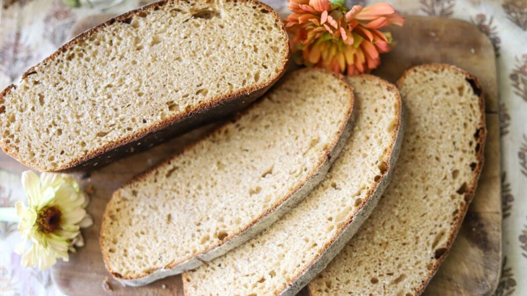 Freshly sliced whole grain sourdough bread on cutting board with flowers