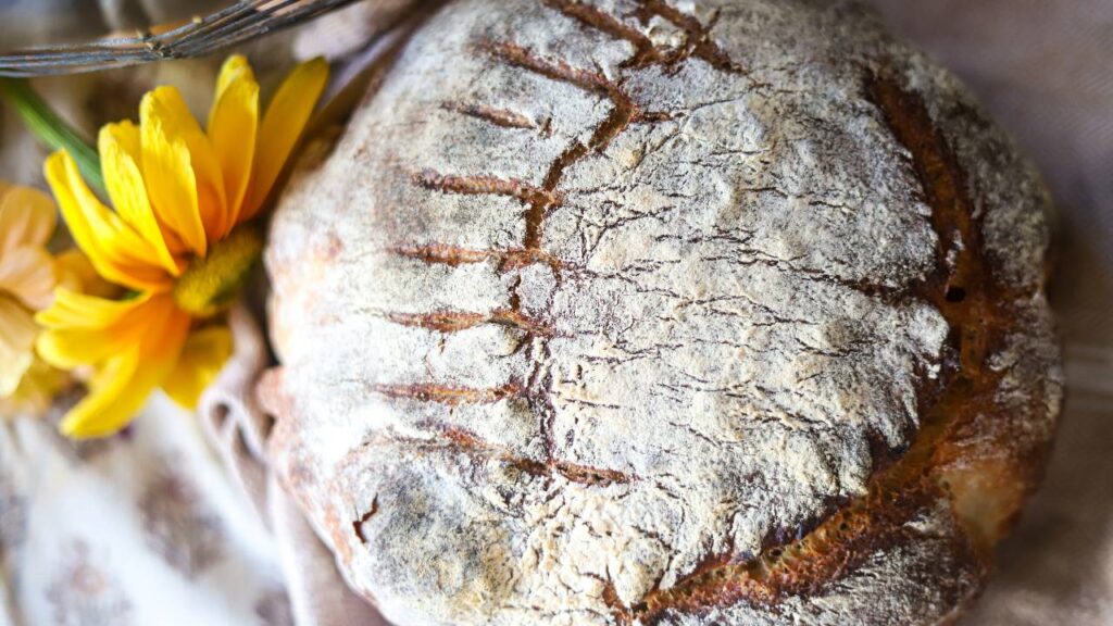 Rustic sourdough boule with decorative scoring and flour-dusted crust