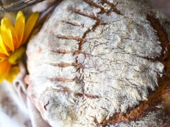 Rustic sourdough boule with decorative scoring and flour-dusted crust