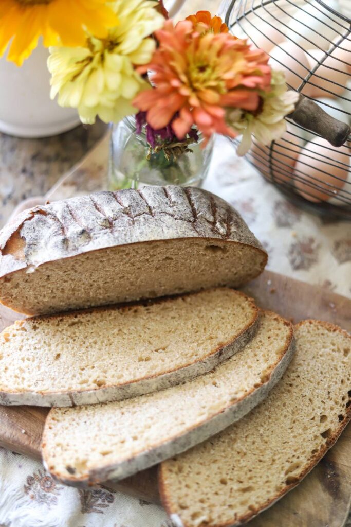 Whole grain sourdough bread slices next to fresh flowers and eggs