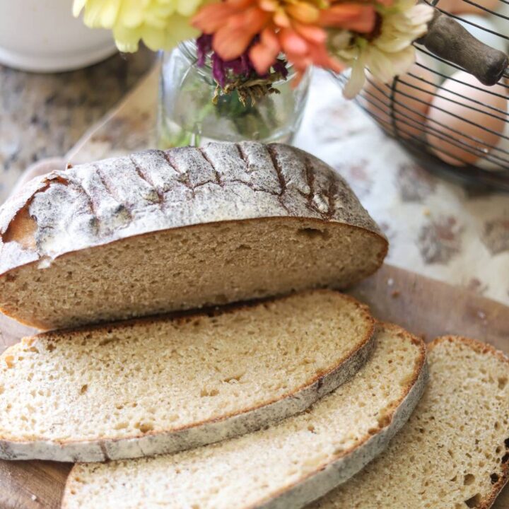 Whole grain sourdough bread slices next to fresh flowers and eggs