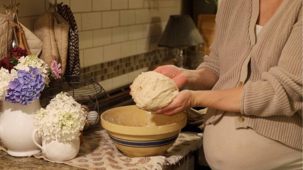 Hands holding freshly mixed sourdough dough over bowl