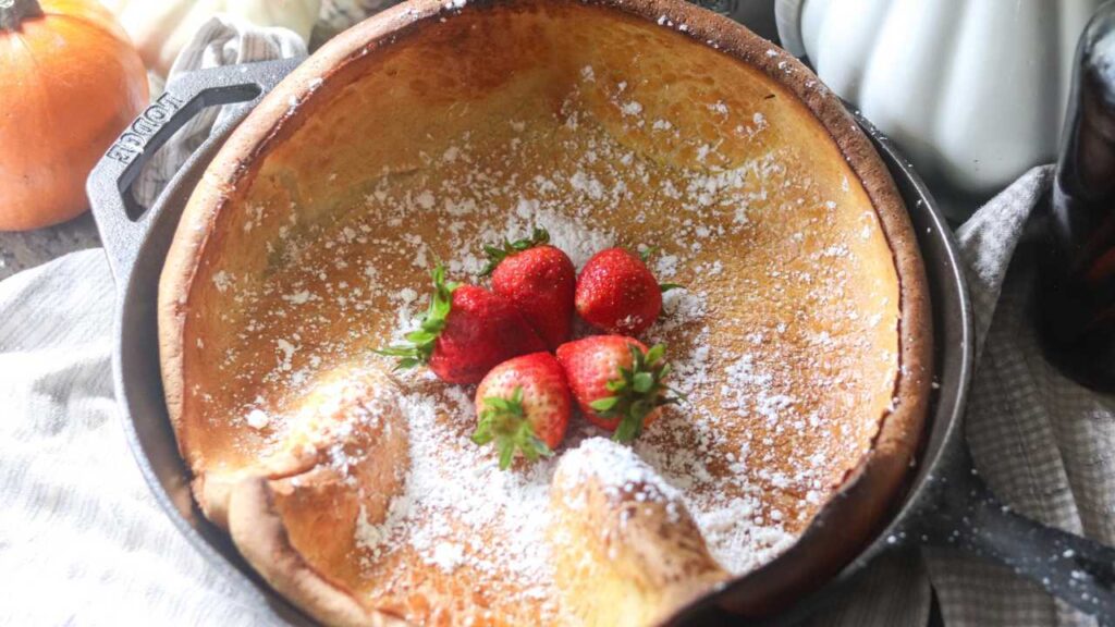 dutch baby pancake in a cast iron with strawberries on top