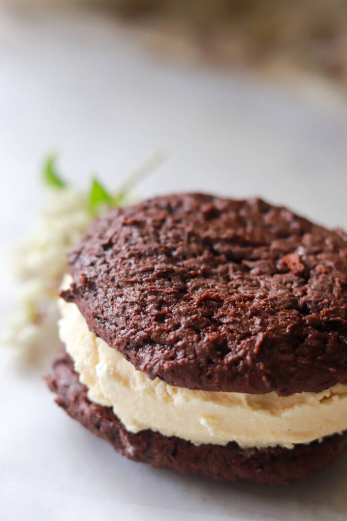 Stacked chocolate ice cream sandwiches with a single one in focus at the front.
