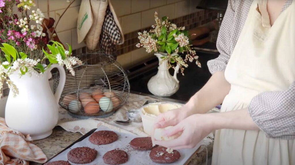 A person assembling ice cream sandwiches with chocolate cookies and vanilla ice cream.