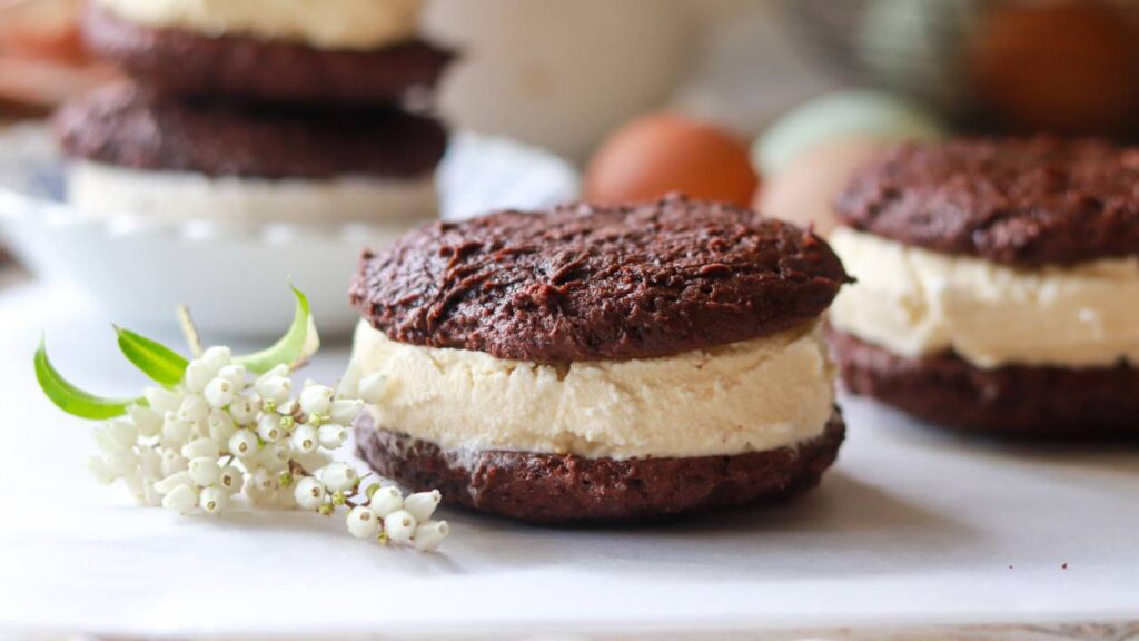 Close-up of a chocolate cookie ice cream sandwich on parchment paper.