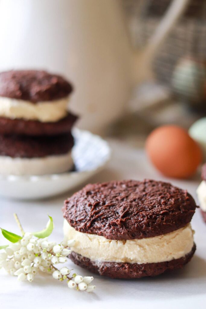 Chocolate cookie ice cream sandwich with eggs blurred in the background.