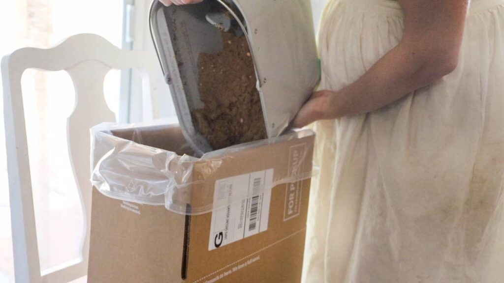 Person emptying the Mill food recycler bucket into a shipping box.