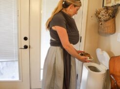 Woman adding kitchen scraps into a Mill food recycler in her home.