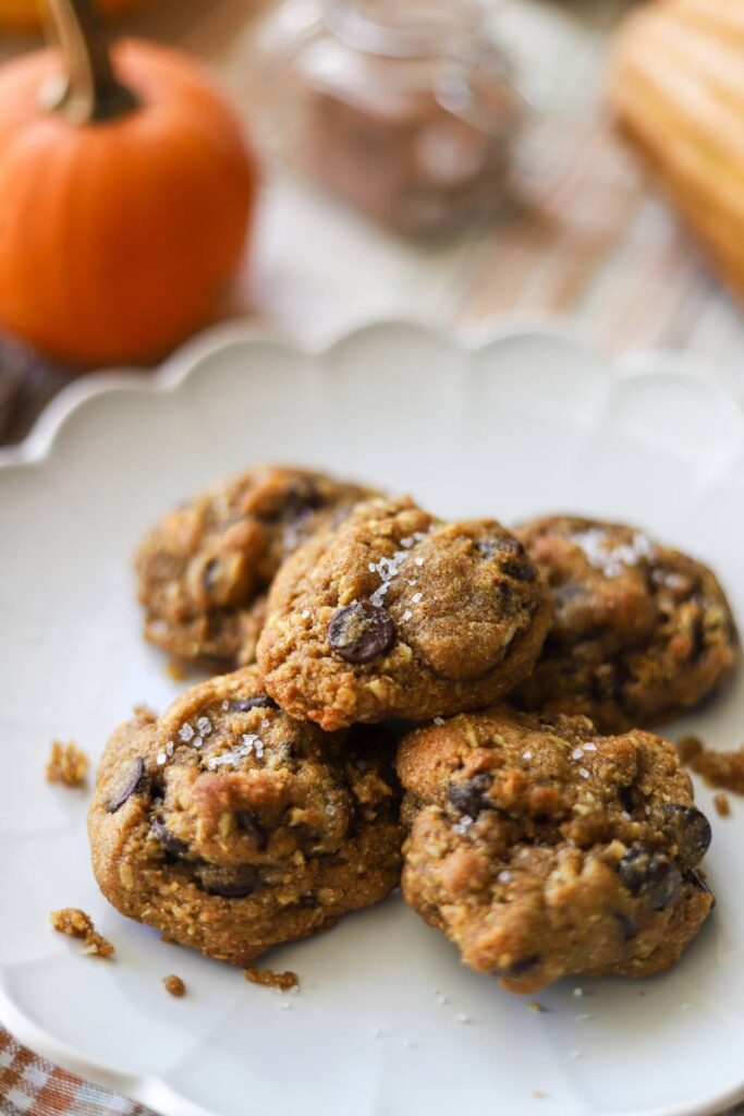 Pumpkin coconut chocolate chip cookies stacked on a white plate