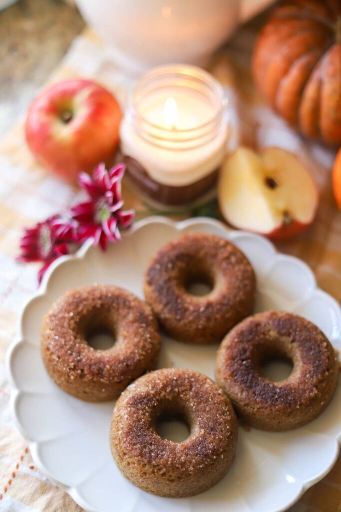 Whole grain apple cider donuts on a plate with apples and fall decor