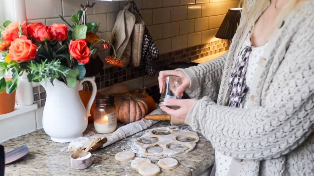 Person cutting out sugar cookie dough in a cozy kitchen