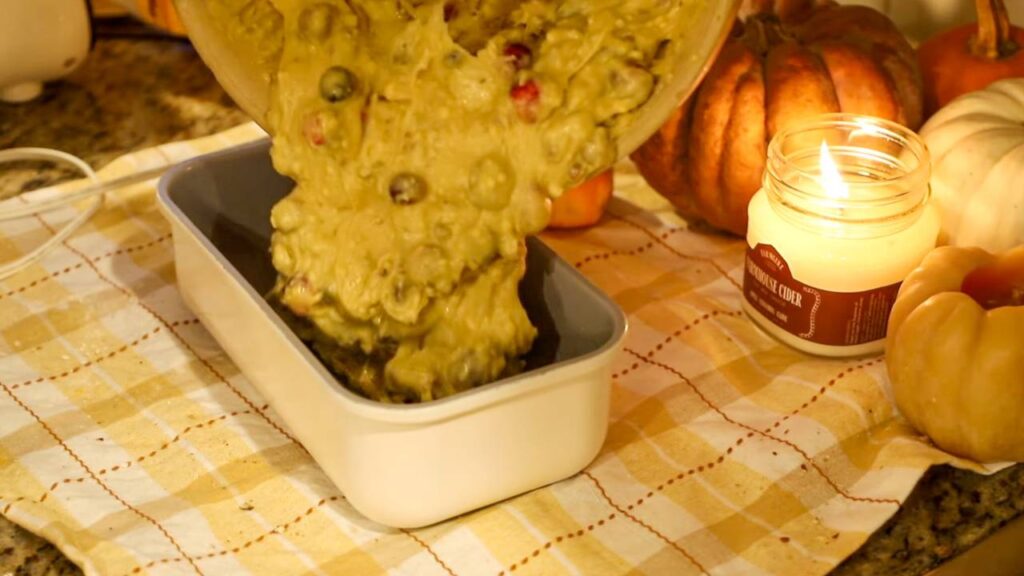 Pouring cranberry orange bread batter into a loaf pan